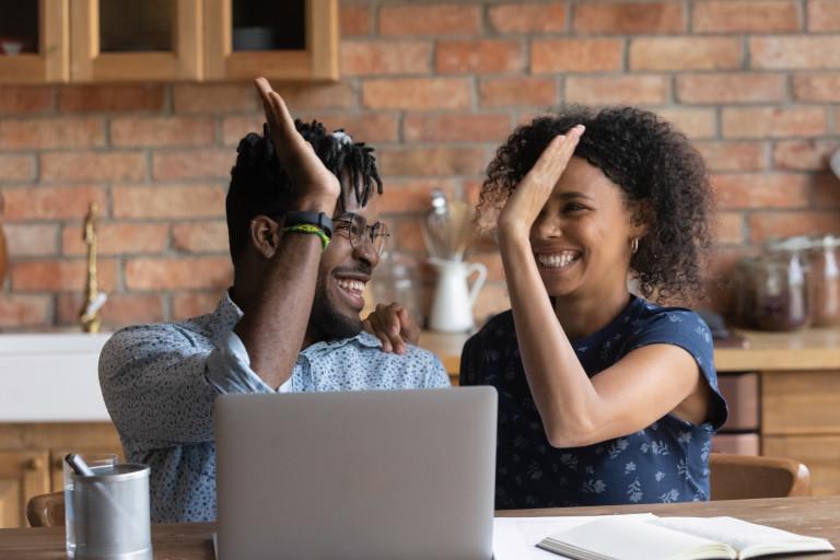 A couple going over finances and high-fiving. 