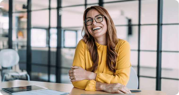 Portrait of a smiling businesswoman sitting at a desk in her office and looking at camera.