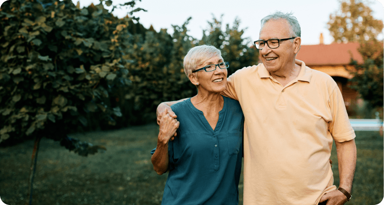 Happy senior couple enjoying while walking embraced in their backyard.